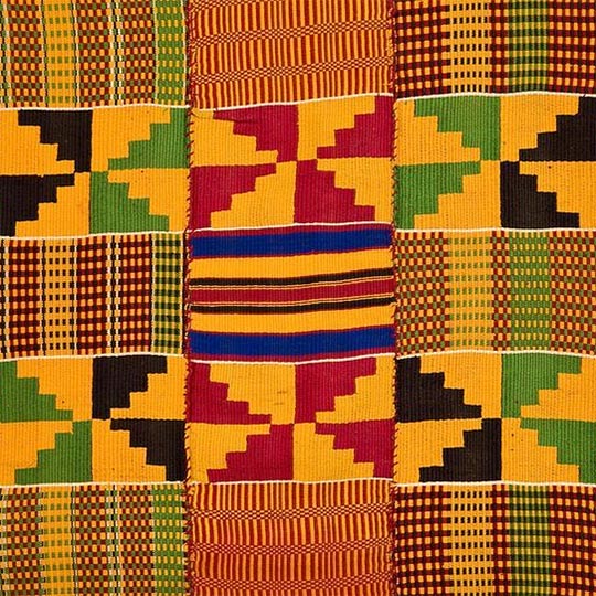A colourful woven kente cloth in yellow, red, green and black patterns.