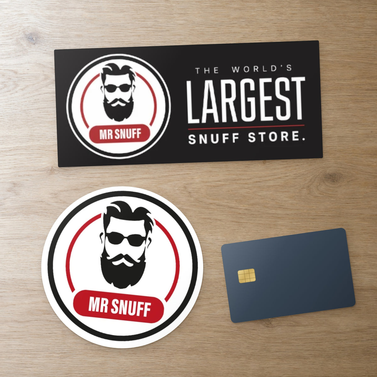 Mr Snuff bumper sticker (180 x 80 mm) and round sticker (110 mm) beside a bank card for scale